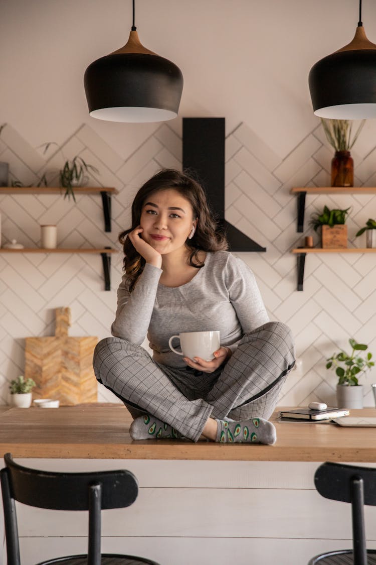 Happy Ethnic Woman Sitting At Table With Cup Of Drink