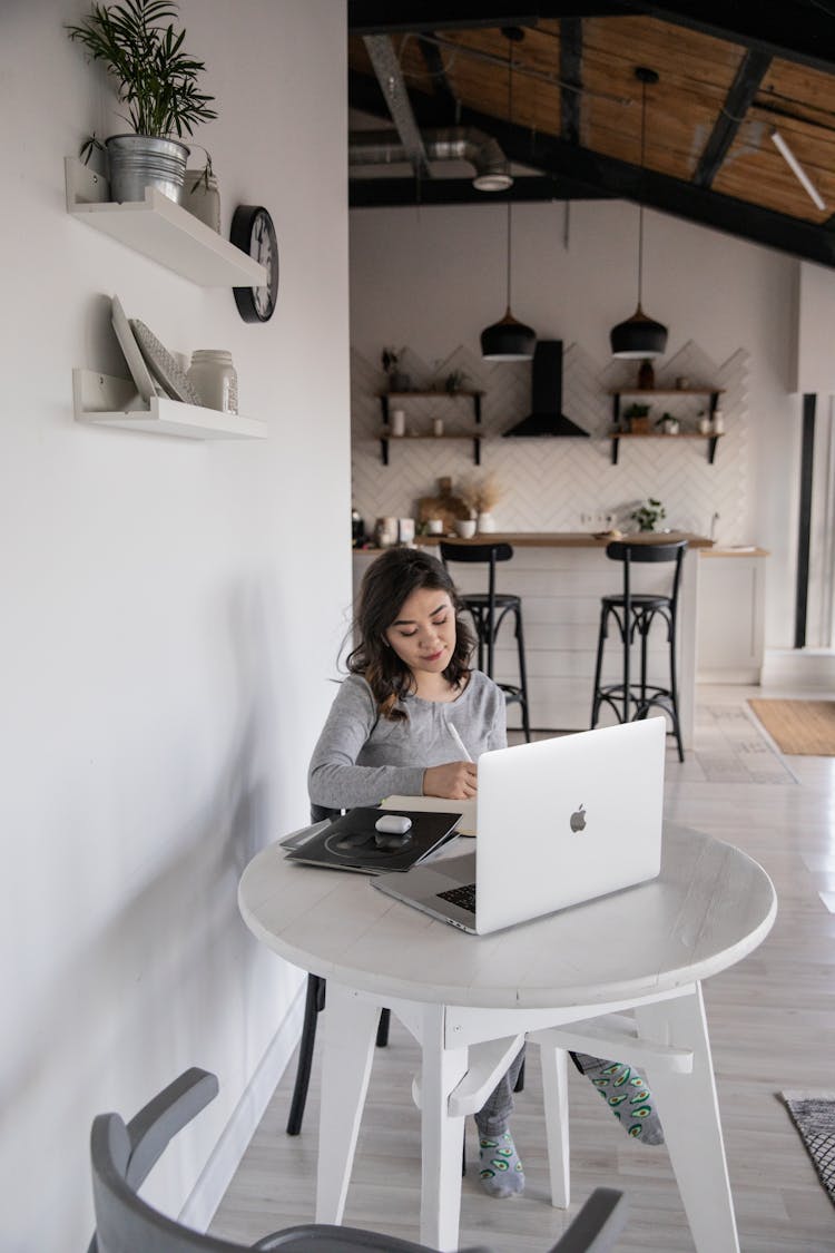 Ethnic Student Writing In Notebook Sitting With Open Laptop