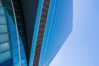 现代玻璃摩天大楼在晴朗的蓝天下低角度映照，展现了当代建筑的特色