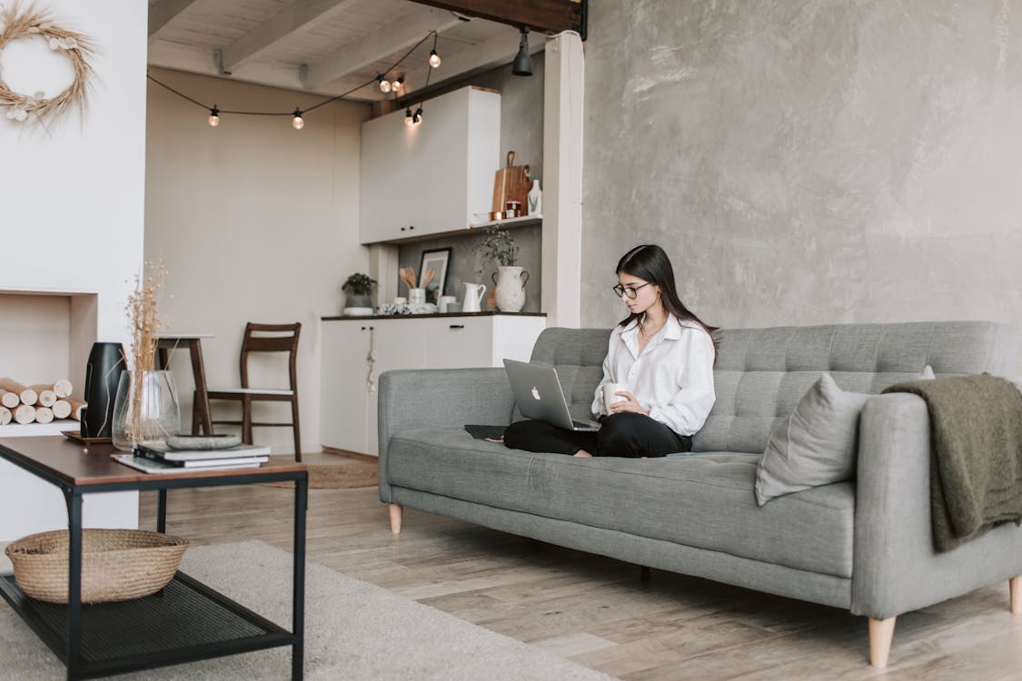 Free Woman Sitting On A Sofa While Working With Laptop Stock Photo