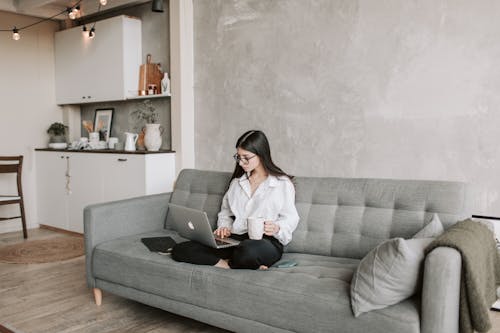 Free Woman Sitting On Sofa While Working At Home Stock Photo