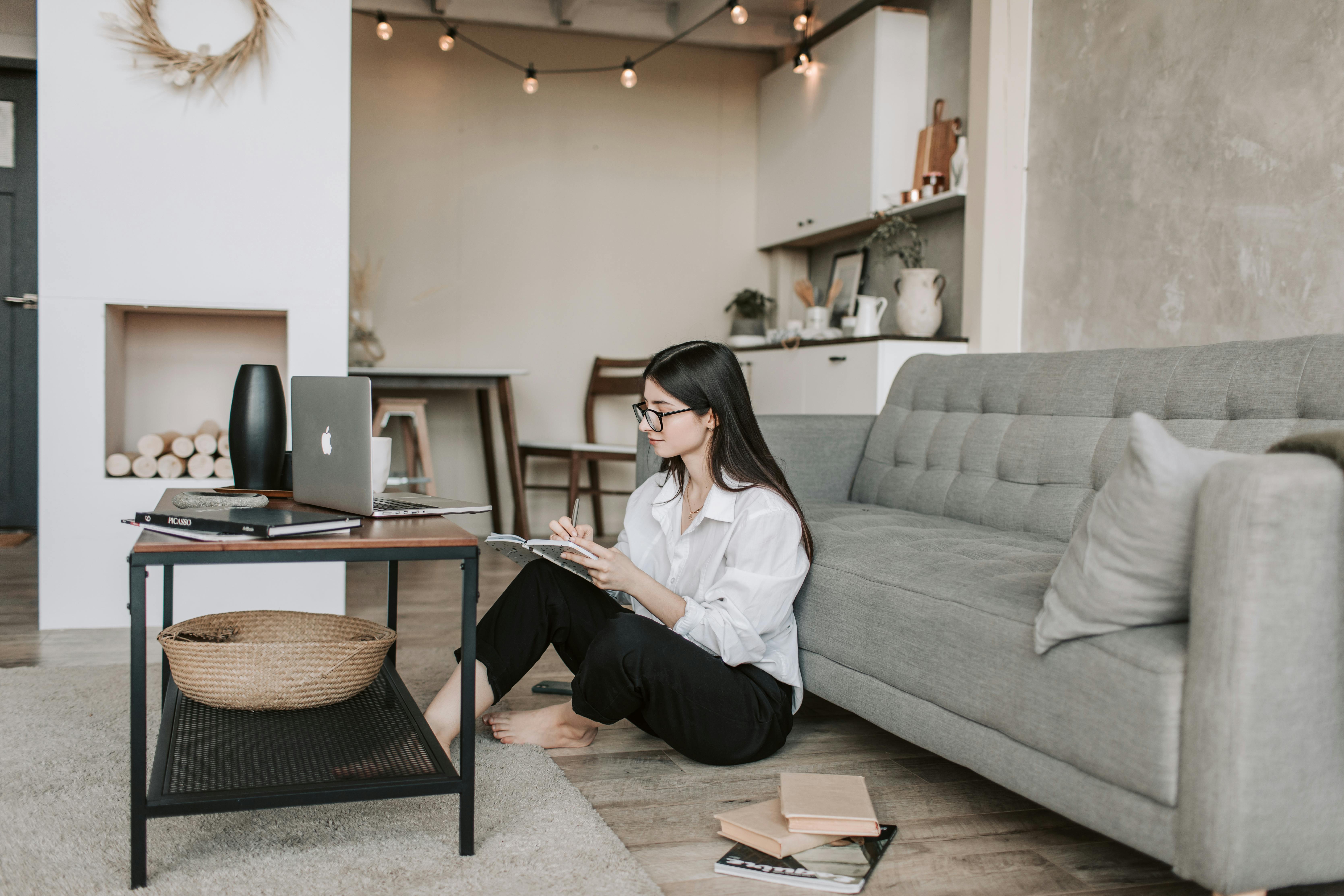 woman taking notes while working with a laptop