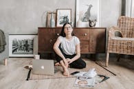 Pensive young lady sitting on rug in modern apartment