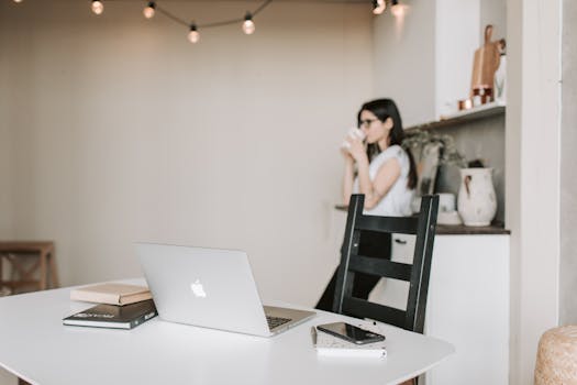 A woman enjoying a coffee break in a stylish home office with a laptop and smartphone.