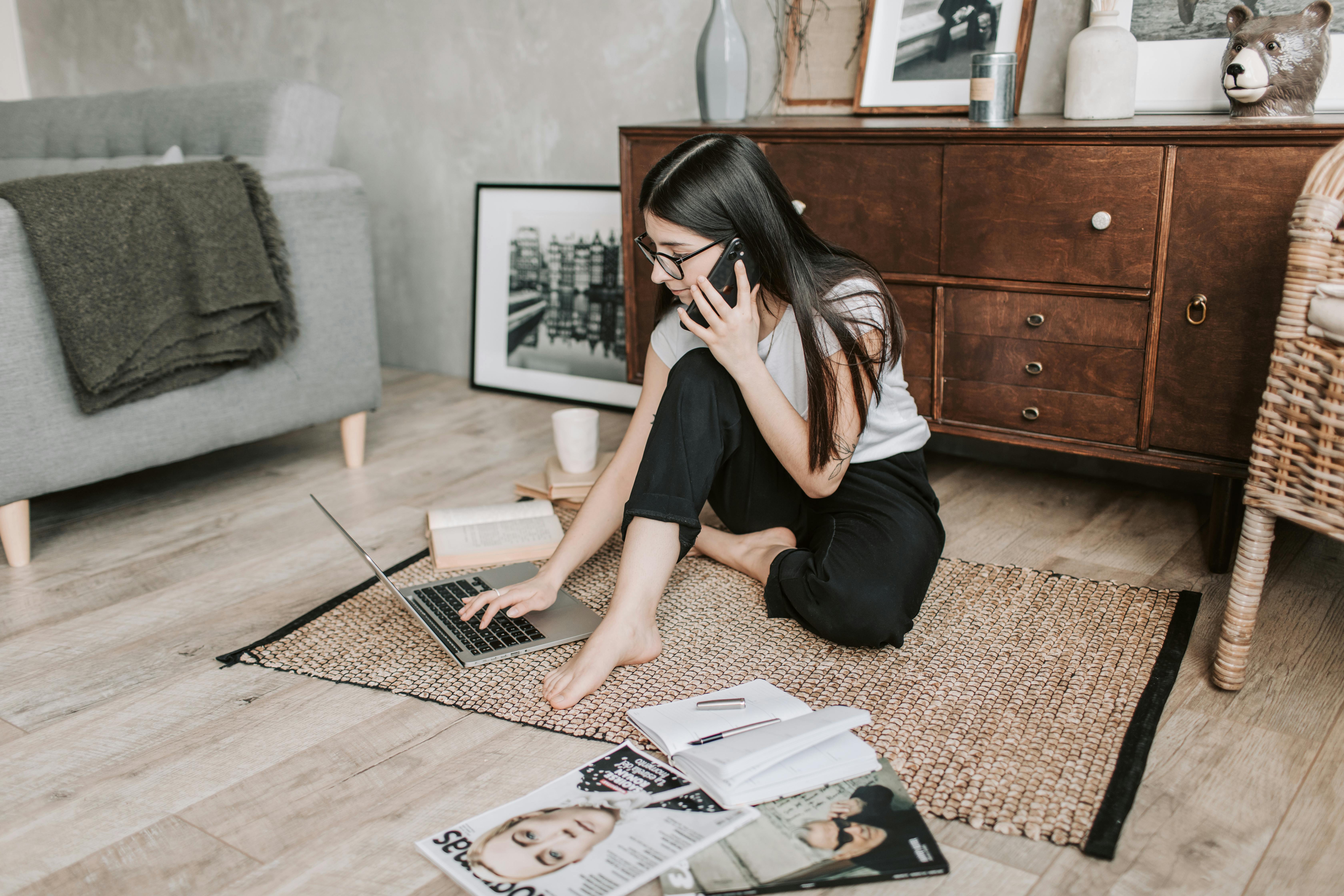 woman using her laptop while having a conversation over the phone