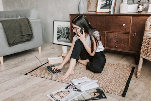 Woman Using Her laptop While Having A Conversation Over The Phone