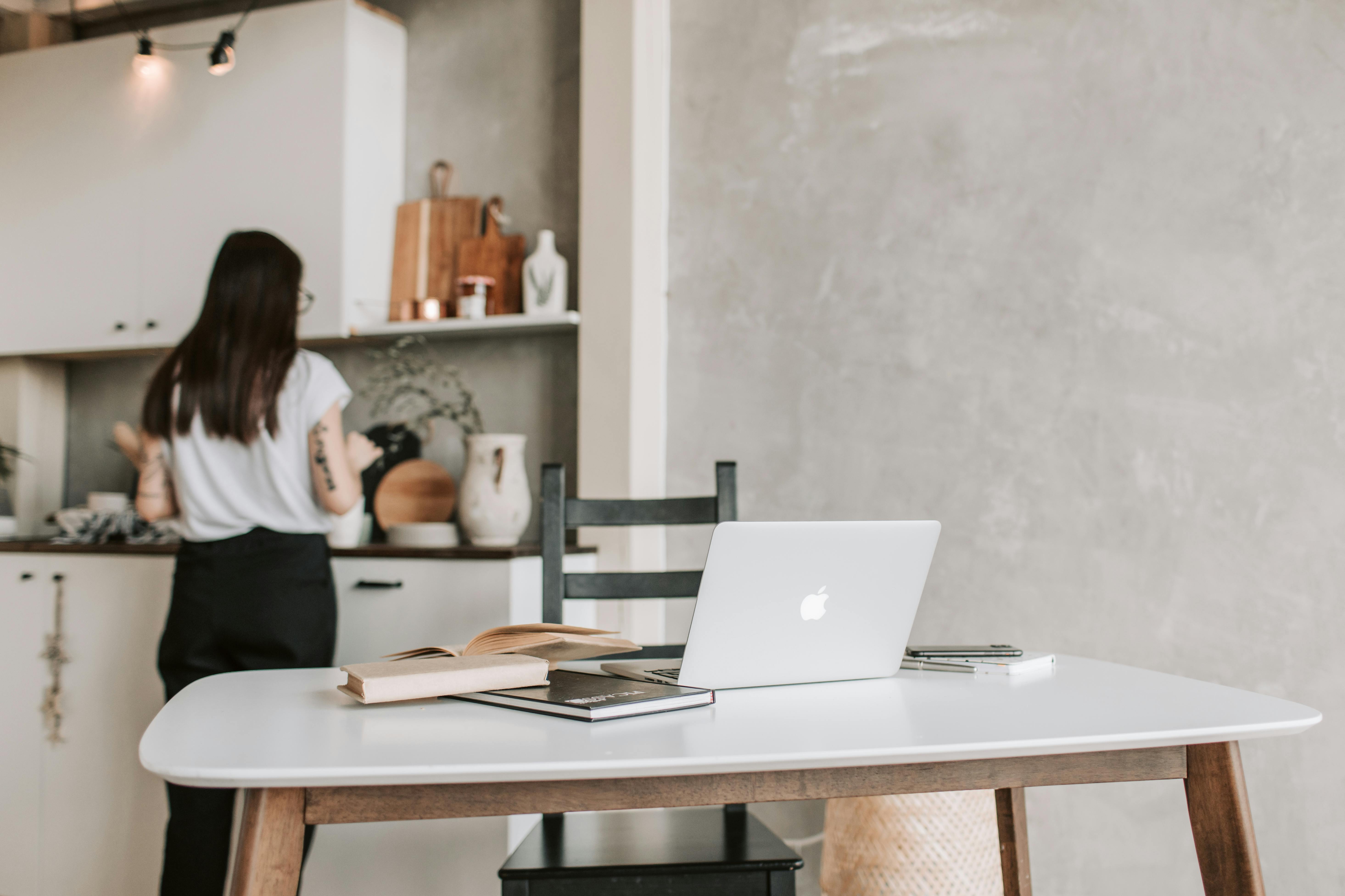 woman standing near the kitchen counter with her laptop open on table