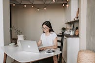 一位年轻女性在时尚的家庭办公环境中专注地使用笔记本电脑处理远程工作任务