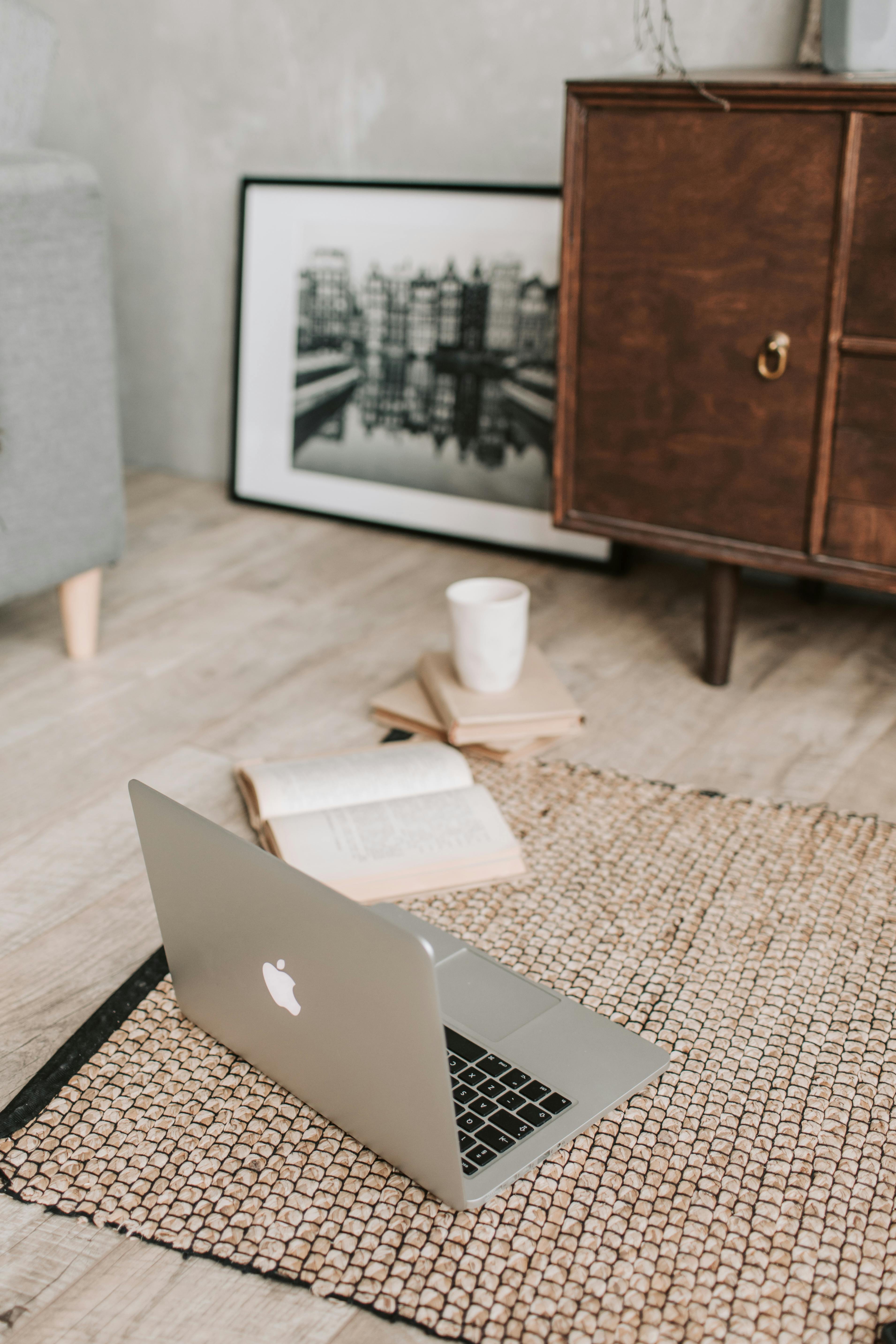 laptop and books on floor carpet