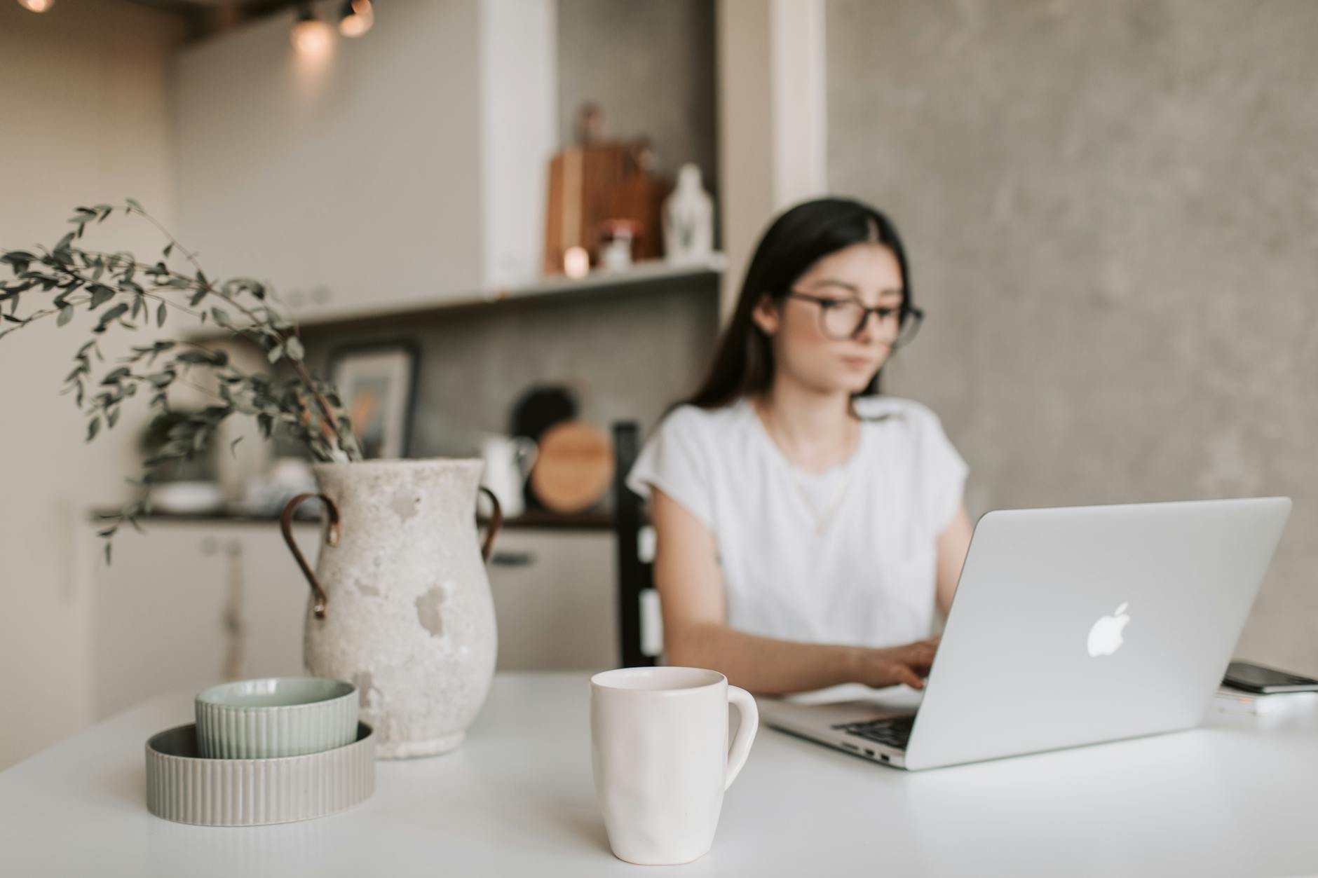 Focused woman working remotely from home using a laptop. Cozy, modern interior with natural elements.