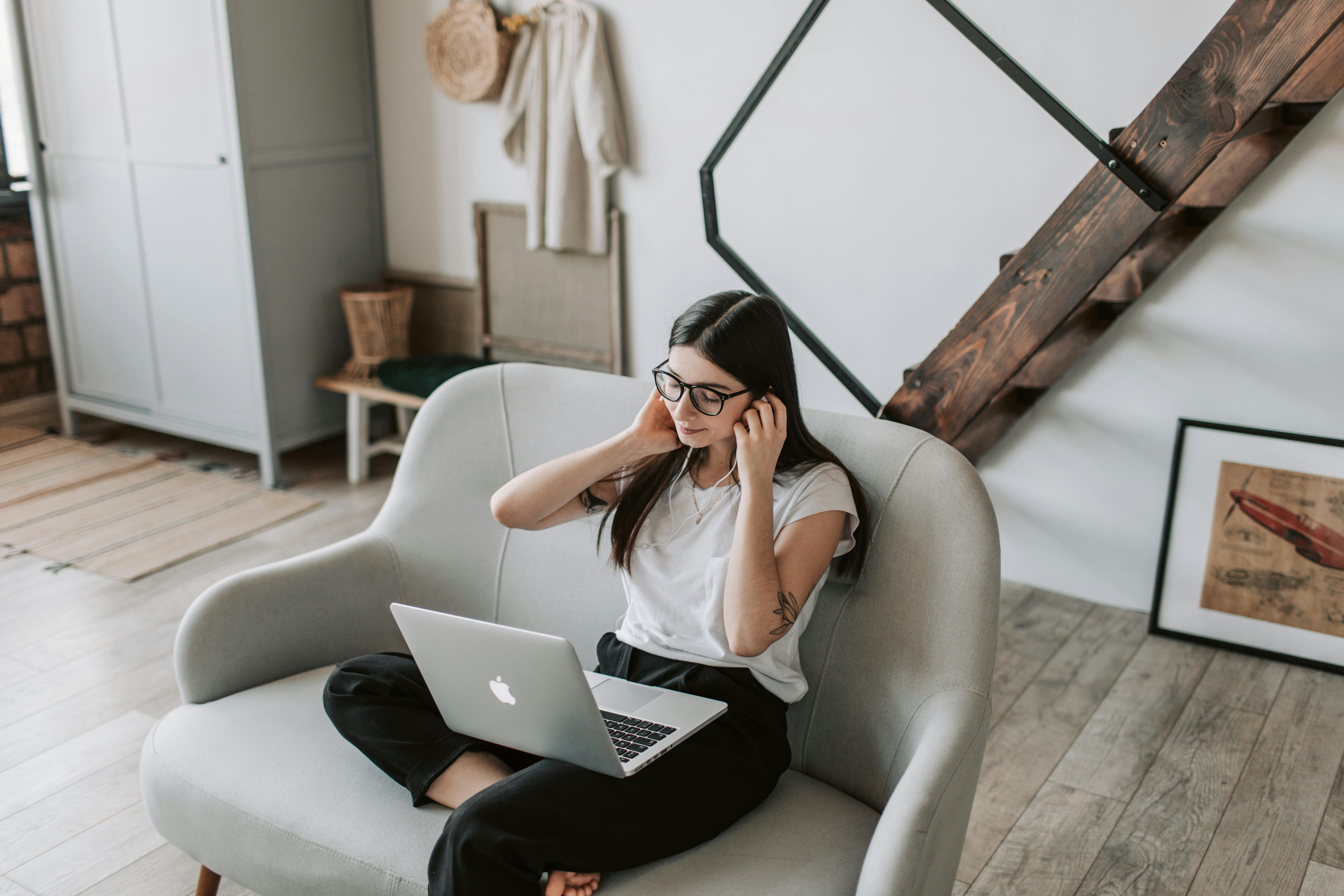 positive woman using earphones and laptop at home during free time