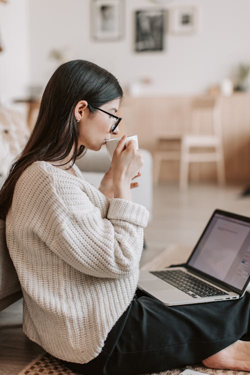 Young businesswoman using laptop while drinking tea at home