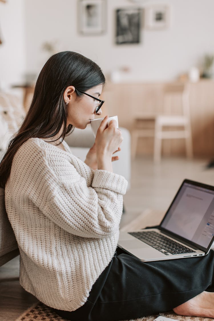 Young Businesswoman Using Laptop While Drinking Tea At Home