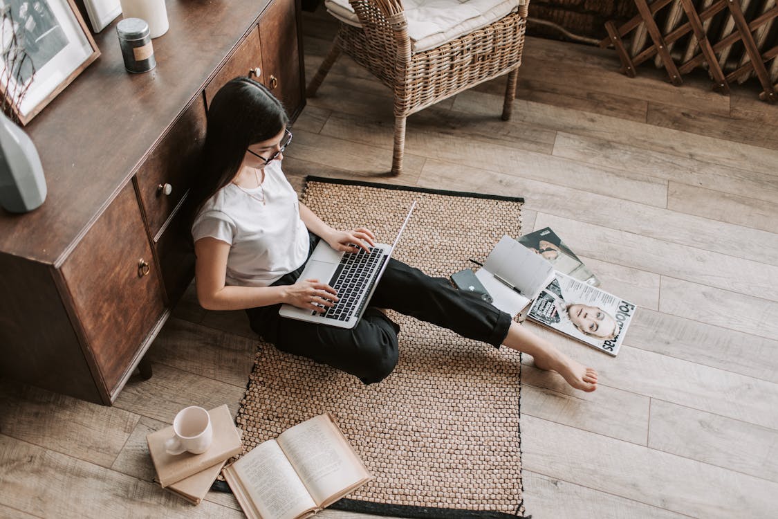 Free Confident young businesswoman with laptop and notebook sitting on floor modern apartment Stock Photo