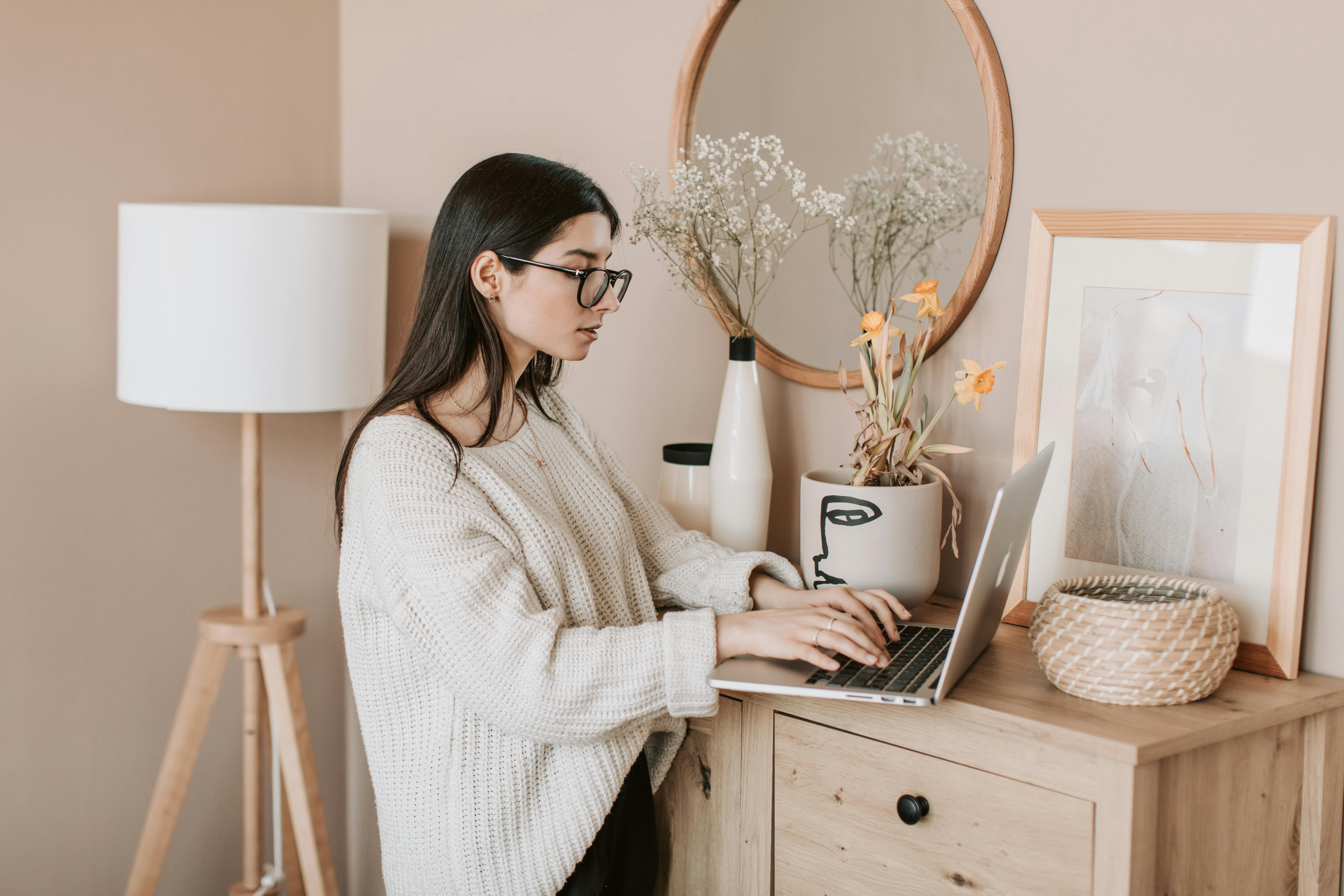 young woman typing on keyboard of laptop at home