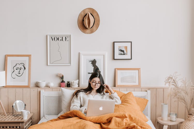 Woman Using Laptop In Bed