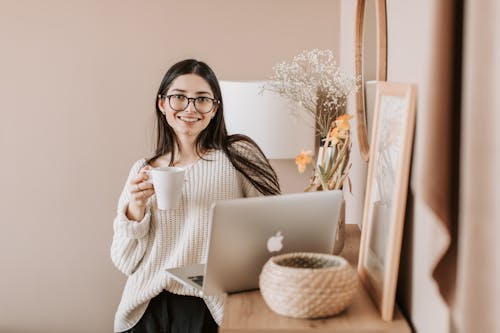Free Woman Standing With A Cup Of Coffee Near A Laptop Stock Photo