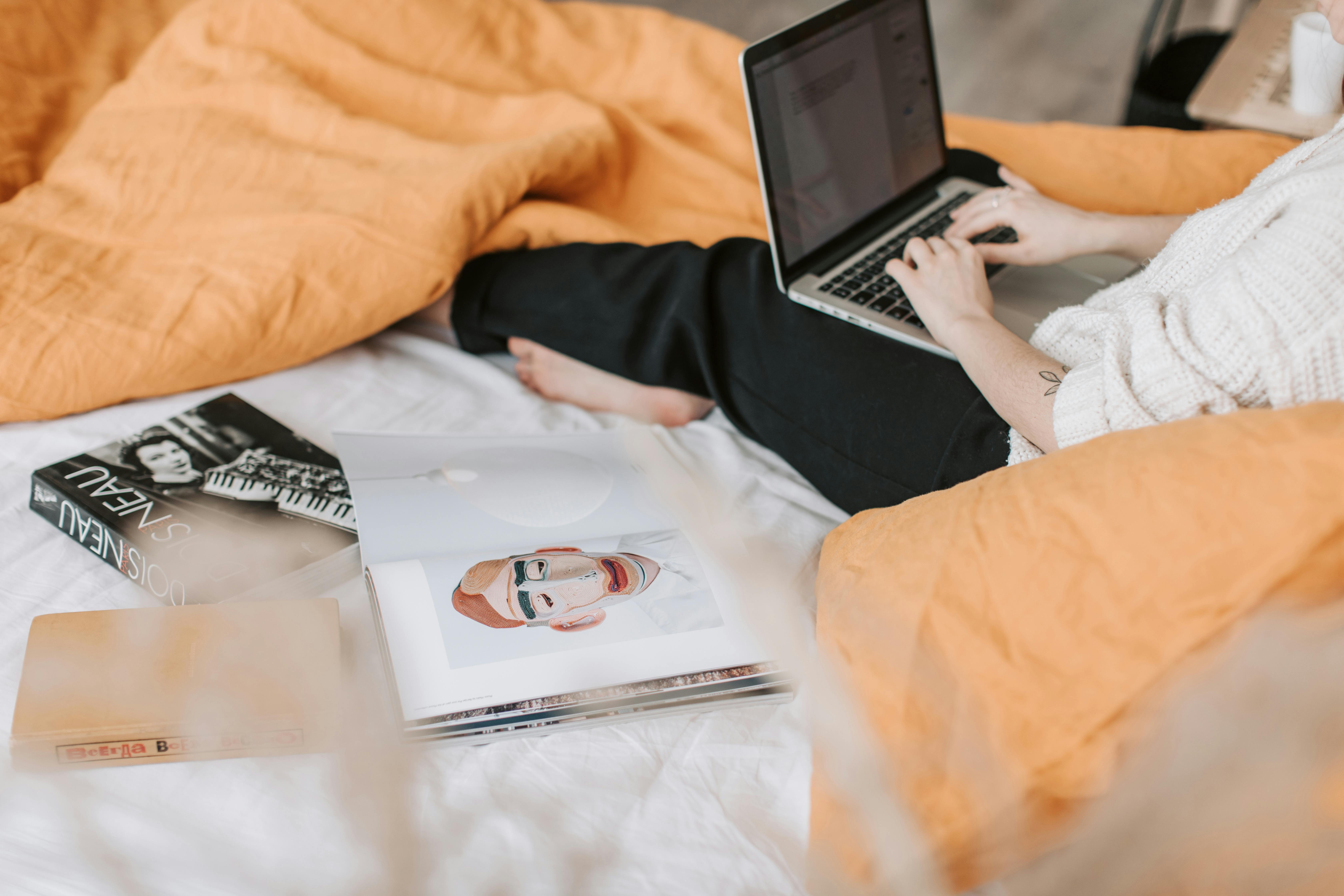 unrecognizable woman typing on laptop on bed