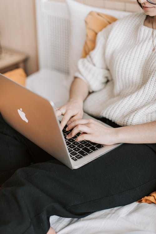 Free Crop woman typing on laptop on bed Stock Photo