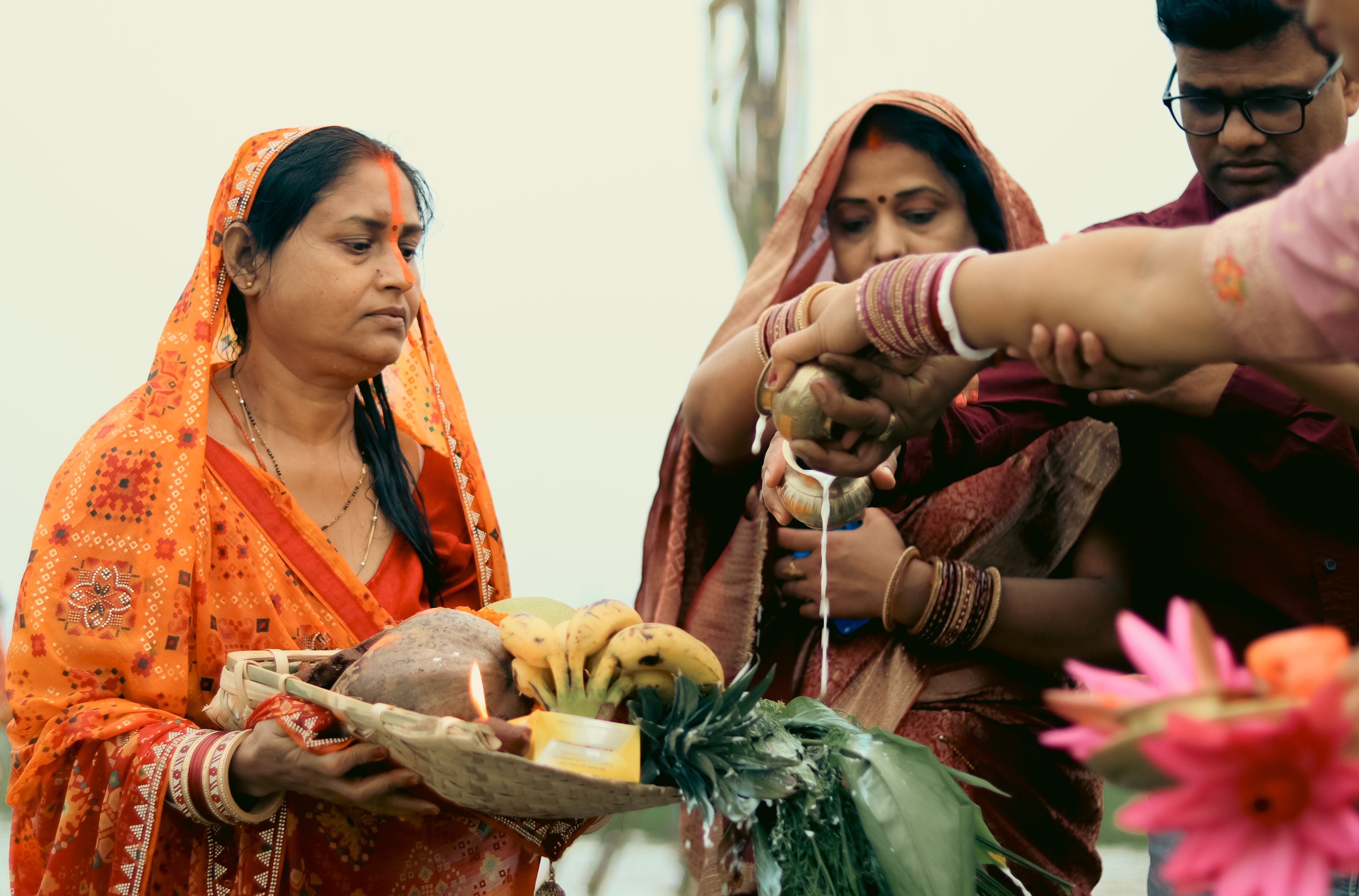Vibrant Chhath Puja ritual in Patna, India, with women in traditional sarees performing offerings.