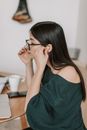 一名妇女在室内办公桌前调整眼镜