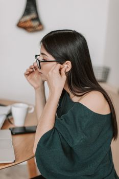 一名妇女在室内办公桌前调整眼镜