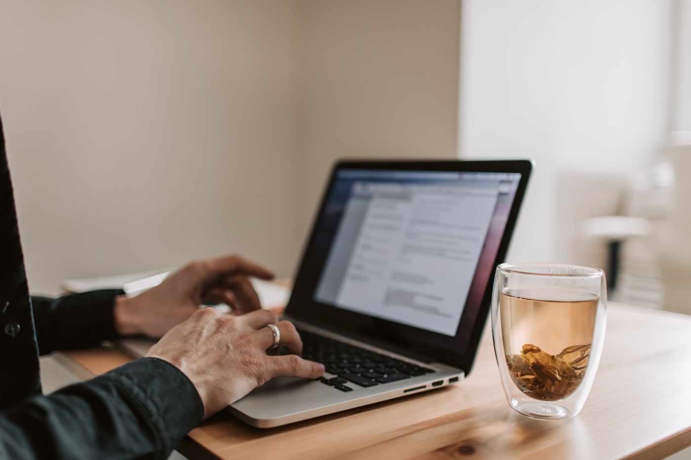 Adult working on laptop with a cup of tea, showcasing remote work lifestyle.