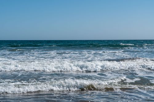 Free A tranquil ocean scene with gentle waves and a clear blue sky, perfect for relaxation. Stock Photo