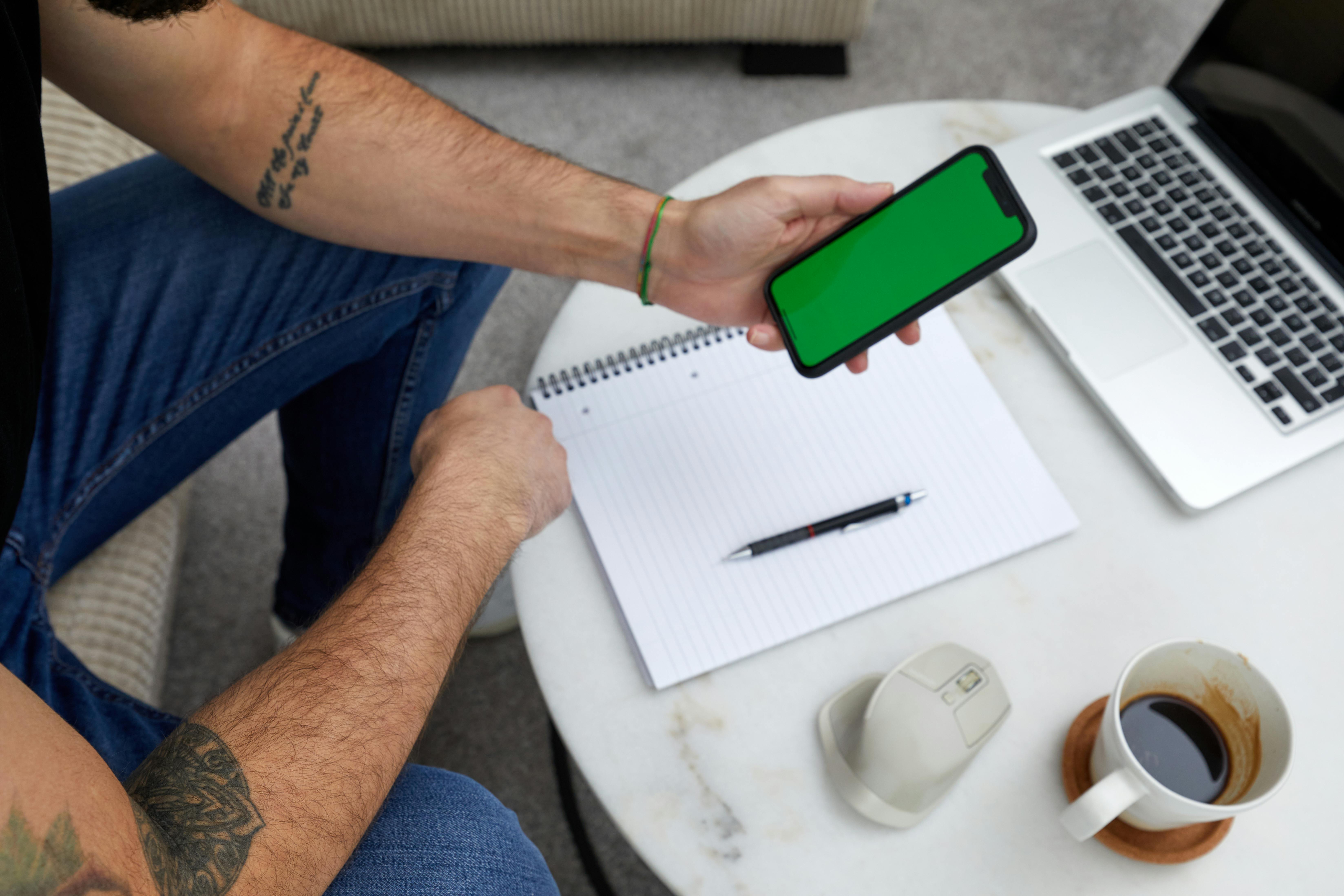 Top view of a modern workspace with a smartphone, laptop, notebook, and coffee.