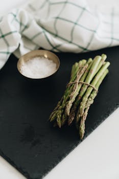 Bundle of fresh green asparagus on slate with salt, perfect for healthy recipes.