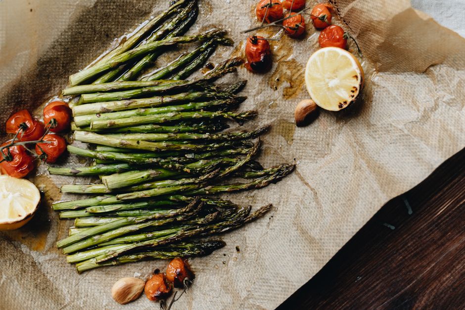 A 9x13 baking dish of golden chicken thighs nestled among lemony orzo, bright green asparagus pieces, and peas, finished with grated parmesan and fresh dill.
