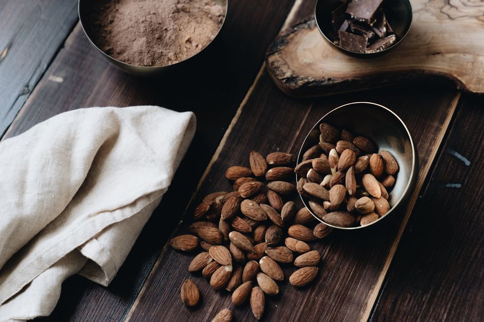 A still life composition with almonds, chocolate, and cacao powder on a wooden surface, creating a warm and delicious atmosphere.