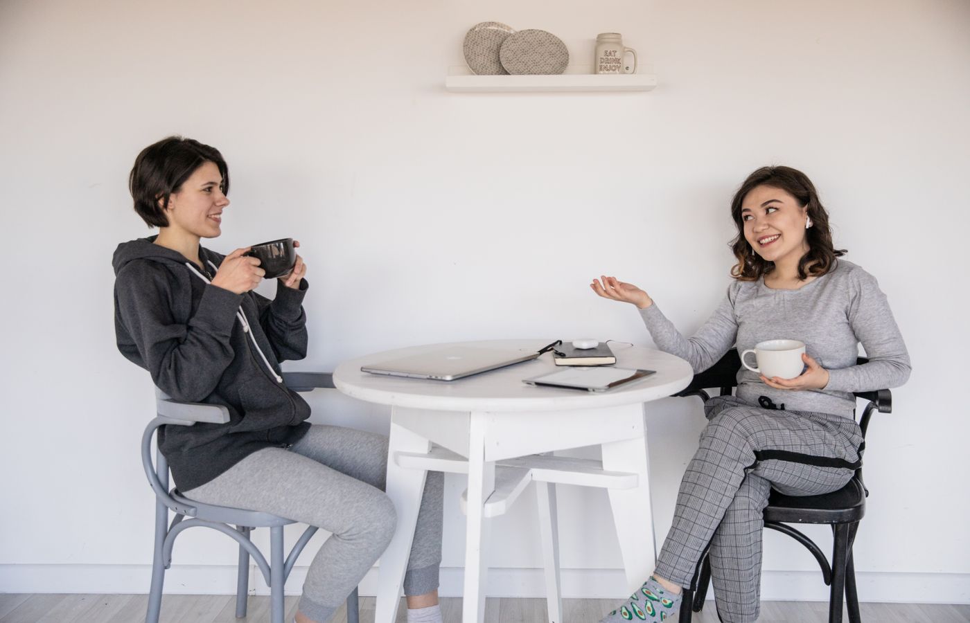 Two women enjoying a friendly chat over coffee indoors, relaxed and smiling.