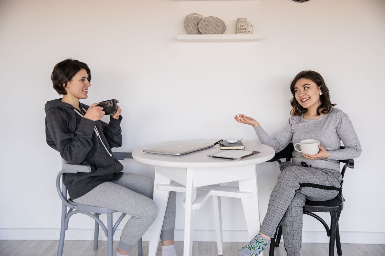 Two women sitting at a table talking and drinking coffee, an example of accountability and support