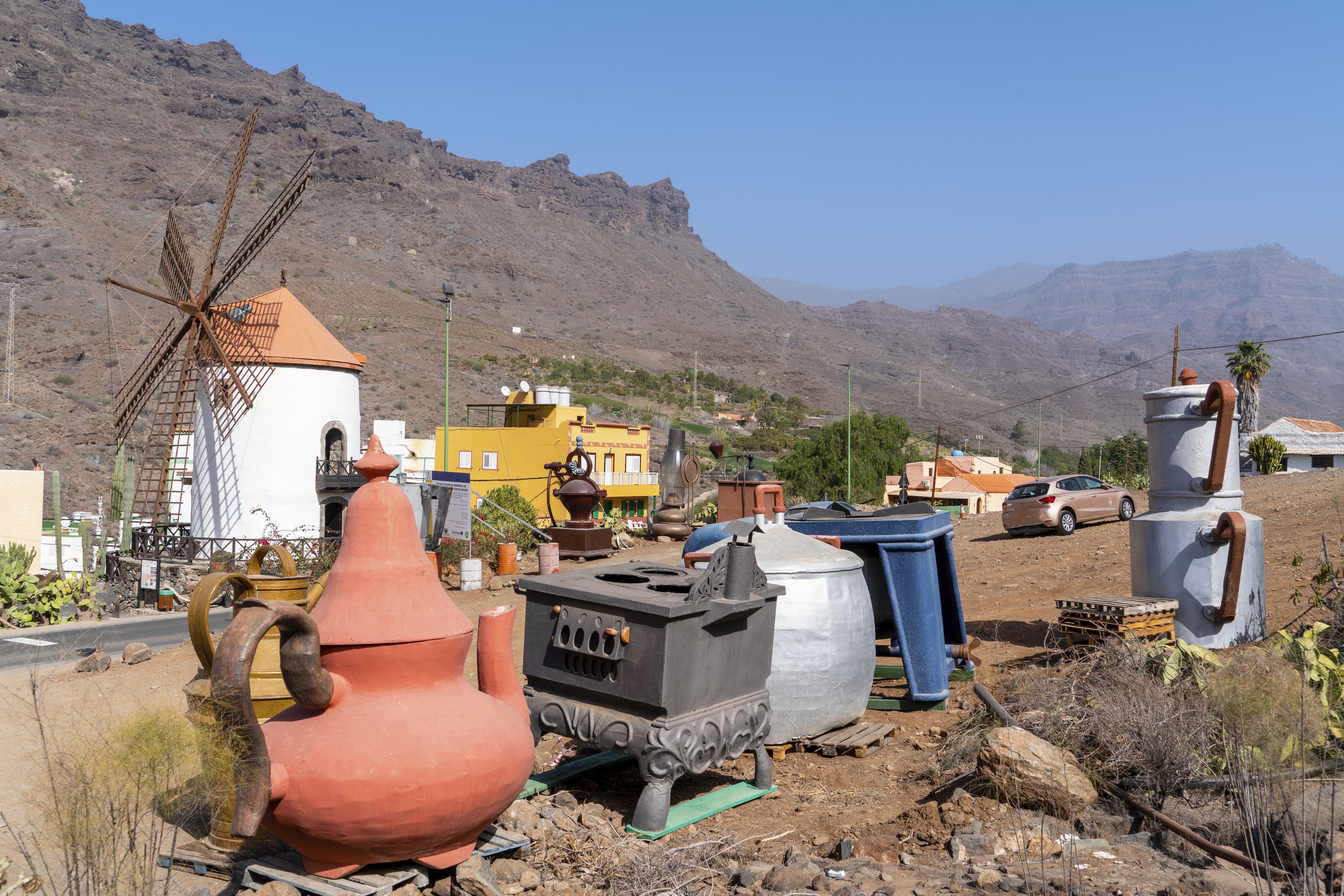 Classic aged windmill at roadside near collection of vintage clay pots and kitchenware in colorful village in Gran Canaria