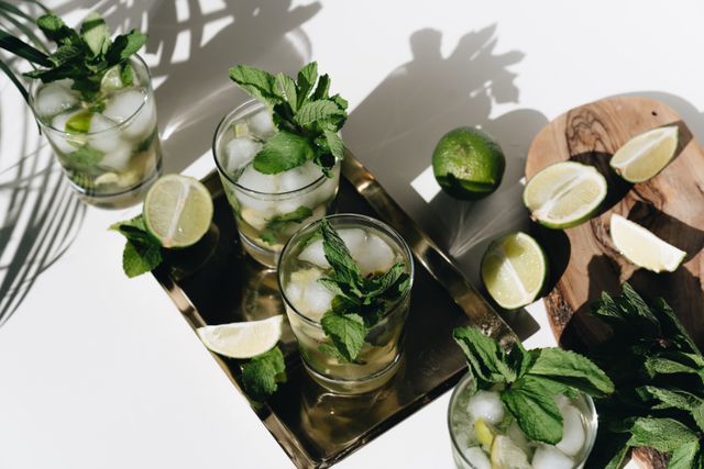 Overhead view of mint and lime mojitos on a brass tray with lime wedges
