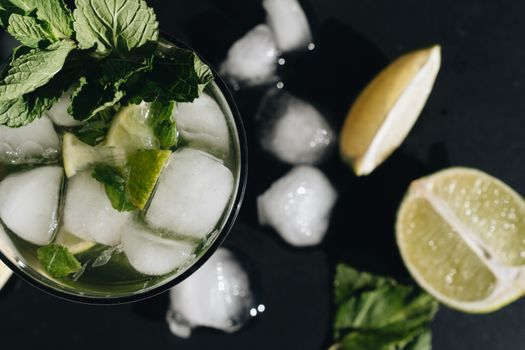 Top view of a refreshing mojito with lime slices and mint leaves, perfect for summer cooling.