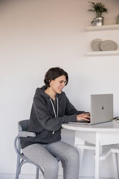 Young woman in casual wear using laptop for remote work at home. Bright and modern indoor setting.