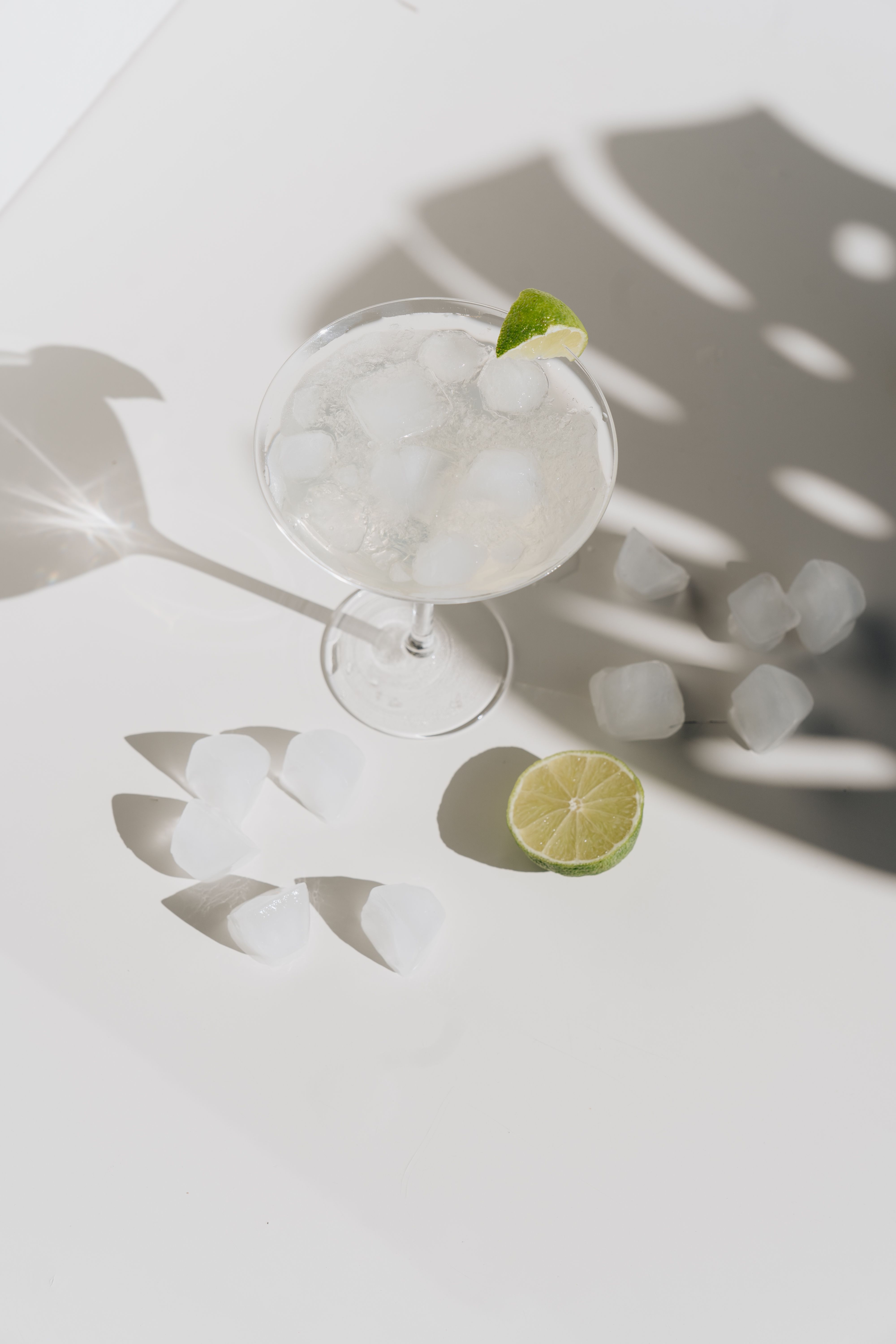 An aerial view of a refreshing lime margarita with ice, casting dramatic shadows.