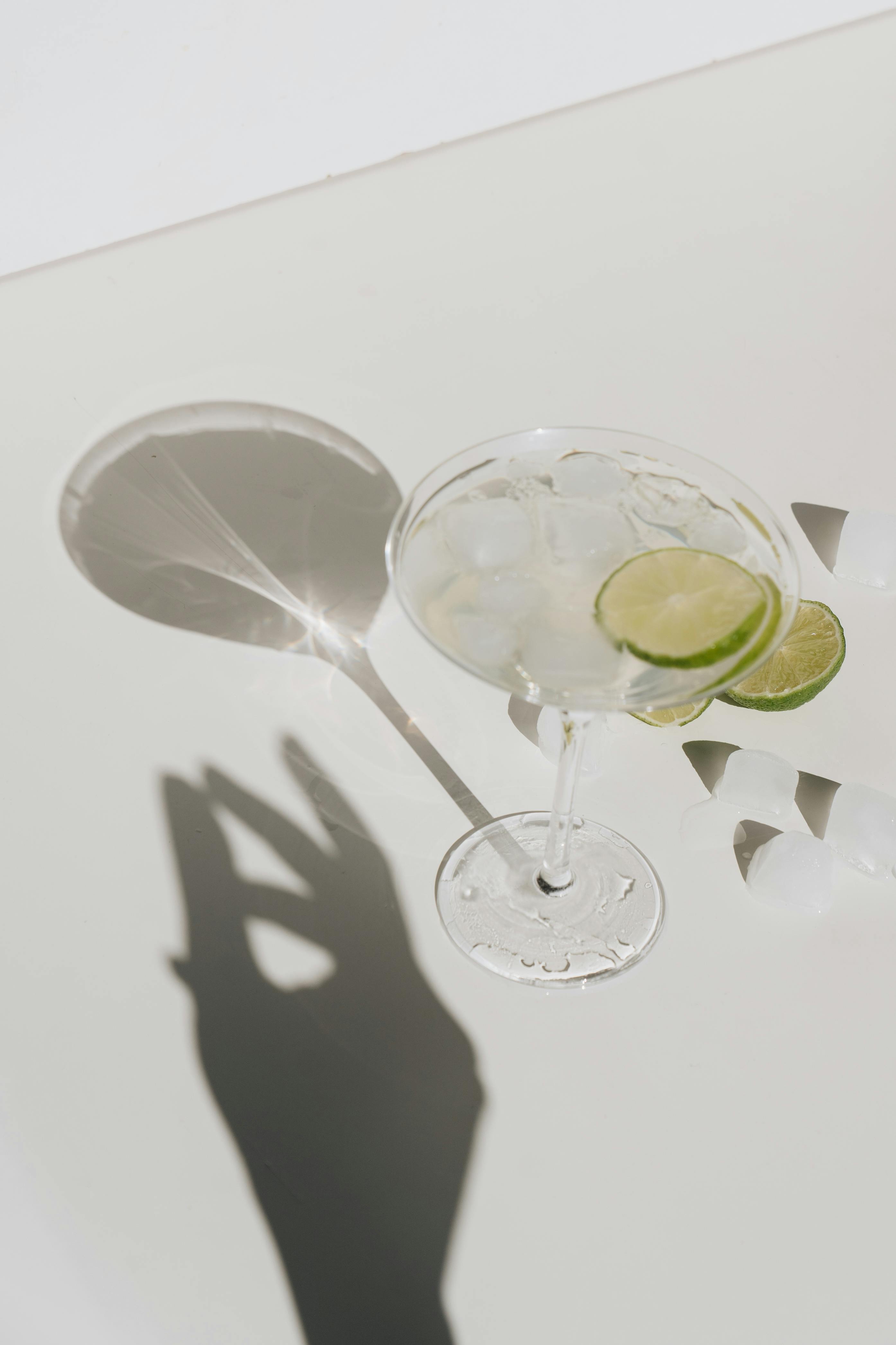 Stylish glass of margarita with lime slices and ice cubes casting a shadow.