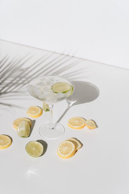 Chilled margarita with lime and lemon slices on a sunny table, refreshing summer vibe.