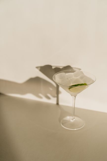 Elegant cocktail in a glass with a lime slice, casting a shadow. Perfect for refreshing summer drinks.
