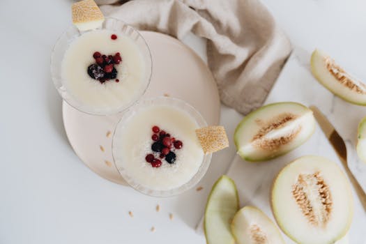 Creamy melon dessert with fresh berries in glass bowls, perfect for a summer treat.