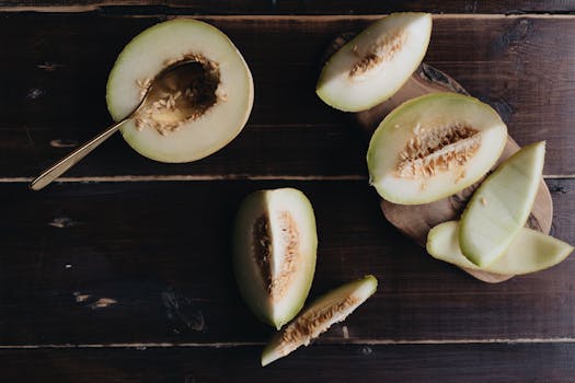 A top view of fresh cantaloupe slices on a dark wooden surface, showcasing healthy and vibrant fruit.