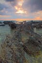 一个宁静的海岸场景，以崎岖的岩石和绚丽的日落天空为特色