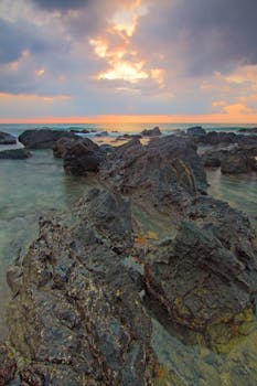 一个宁静的海岸场景，以崎岖的岩石和绚丽的日落天空为特色