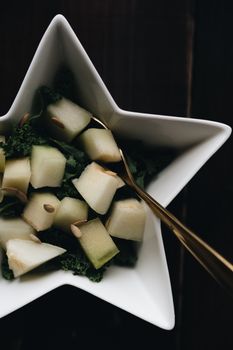 A refreshing cantaloupe salad served in a star-shaped bowl on a dark wooden table.