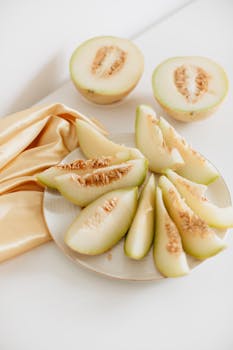 Delicious honeydew melon slices on a plate with beige fabric for a fresh and elegant food presentation.