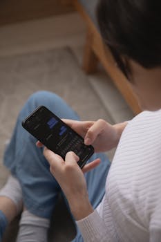 A woman using a smartphone to text, captured from above, indoors setting.