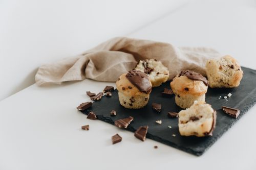 Free Delicious chocolate chip muffins arranged on a black slate with scattered chocolate pieces. Stock Photo